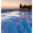 19. Mai, Kalksinterterrassen in Pamukkale, Türkei. Stufen aus blauem Wasser und weiße Terrassen vor Abendhimmel und Bäumen.