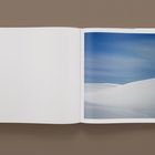 Links steht "158". Rechts ein Foto von schneebedeckten Dünen unter blauem Himmel.