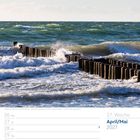 17. Woche, April/Mai 2027. Ein Holzsteg ragt ins Meer, die Wellen brechen daran bei sonnigem Wetter.