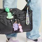 Bunte Perlen formen den Text „DARE TO DREAM“. Schlüsselanhänger mit bunten Tierfiguren an einer schwarzen Tasche.