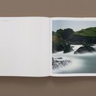 Links steht "Cornwall and Wales" und "163". Rechts ein Foto von klippenreicher Küste mit grünen Hügeln und Nebel.