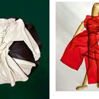 Links ein beiger Trenchcoat auf schwarzem Schirm, rechts Holzpuppe mit rotem Stoffmantel.