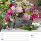 "06 Do Christi Himmelfahrt. 18. Woche, Mai 2027. Blumenarrangement mit Pfingstrosen und Glockenblumen in einer Holzkiste."