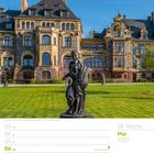18. Woche, Mai 2027. Schloss Lieser, Rheinland-Pfalz. Eine Statue vor einem historischen Gebäude mit grünem Rasen.