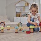 Ein kleines Mädchen spielt mit einer Holzkugelbahn. Im Hintergrund ist ein weißes Regal mit Deko.