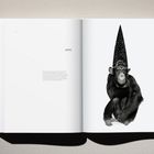 Seite links: "Hugh Monkey." Rechts: Schimpanse mit schwarzem, spitzem Hut, sitzt mit verschränkten Armen.