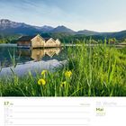 Mai 2027, 20. Woche. Pfingstmontag ist am 17. Bootshäuser am Kochelsee, Bayern. Klarer Himmel, Berge im Hintergrund.