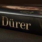 Buchtitel "Dürer" in großen, goldenen Buchstaben auf einem Buchcover mit einem dunklen Hintergrund.