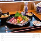 "Sashimi-Platte in einem Restaurant" steht im Bild. Eine speckierte japanische Holzplatte mit Sashimi und Beilagen.