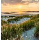 28. Juli, Sonnenuntergang auf Langeoog. Dünengras, Sandstrand, ruhiges Meer, orangefarbener Himmel mit Wolken.