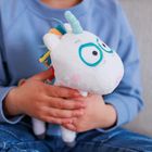 Ein Kind hält ein weißes Stoff-Einhorn mit blauen Augen und bunter Mähne. Das Kind trägt einen blauen Pullover.