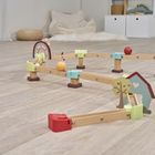 Ein Spielzeug-Parcours auf hellem Holzboden mit bunten Holzelementen, darunter Bäume und ein kleines Haus.