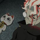 Eine Puppe in Katzenform mit einer Plakette, auf der japanische Schriftzeichen stehen, liegt neben einer Figur mit auffälliger Frisur.