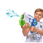 Junge spritzt mit einer Wasserpistole, trägt ein weißes T-Shirt. Wassertropfen und grüne, blaue Farben auf der Pistole.