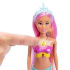 Keine sichtbaren Texte. Eine Puppe mit pinkem Haar und Krone, trägt ein buntes Oberteil. Ein Finger drückt auf ein Halsaccessoire.