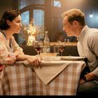 Kein Text. Ein Mann und eine Frau sitzen in einem stimmungsvoll beleuchteten Restaurant am Tisch mit Wein und Essen.