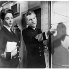 Eine Offizierin hält ein Notizbuch, während ein Offizier mit einem Stift auf eine Karte zeigt.