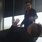 Ein Mann liegt auf einem Tisch, ein anderer beugt sich drohend über ihn. Ein Dritter schaut auf sein Handy.