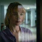 Keine erkennbaren Texte. Eine Person mit geschlossenen Augen in einem blauen Kleid, umgeben von Konfetti und Menschen.