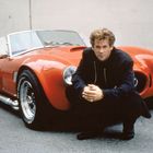 Ein rotes Cabrio mit auffälligen Reifen und einem Mann, der davor hockt.