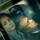 Zu sehen sind eine Frau und ein Mann in einem Zug. Der Mann schläft, während die Frau nachdenklich aus dem Fenster schaut.