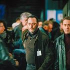 Zwei Männer mit "SÉCURITÉ" Namensschildern in einer Menschenmenge, tragen Lederjacken und wirken aufmerksam.