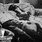 Text: "FBI Agent Eddie wieder colt-richtig." Zwei Menschen liegen schlafend auf einem floral gemusterten Sofa.