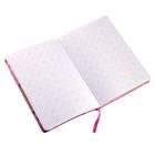 Notizbuch mit rosa geometrischem Gittermuster, aufgeklappt, Buchrücken mit farbigem Design, pinkes Lesezeichenband.