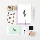 Stempel mit floralen Motiven, Karten und Tags auf weißem Hintergrund, begleitet von einem Stift und einem Stempelkissen.