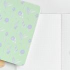 Zwei blumengemusterte Notizbücher, eines in Orange, das andere in Grün, neben einem geöffneten Notizbuch mit punktierten Seiten.