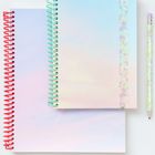 Zwei Notizbücher mit pastellfarbenem Verlauf in Blau, Rosa und Gelb. Spiralbindungen in Rot und Grün. Ein Bleistift daneben.