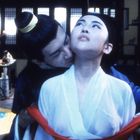 Kein Text vorhanden. Szene mit zwei Menschen in traditioneller asiatischer Kleidung, eine Person wird umarmt.