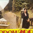 „SODOM 2000“ in roten Buchstaben. Frau in Strümpfen vor Grabsteinen, links ein helles Regenschirm-Studio-Licht.