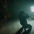 Keine Texte sichtbar. Eine Person kniet vor einem leuchtenden Fernseher in einem dunklen Raum. Atmosphäre mystisch.