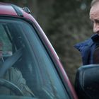 Text: "Gendarmerie". Ein Mann am Steuer schaut zu zwei uniformierten Personen am Autofenster.