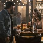 Zwei Flaschen "Corona Extra" und "Pacifico Clara" auf einer Bar. Eine Frau spricht mit einem Mann. Im Hintergrund eine Bar.