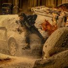 Eine Person springt im Schnee zwischen zwei Autos, daneben eine orange Explosion. Im Hintergrund sind weitere Fahrzeuge zu sehen.