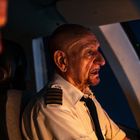 Ich kann keine Texte im Bild erkennen. Zwei Piloten in einem Cockpit, der rechte im Fokus, trägt eine Uniform mit Streifen.