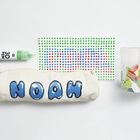 Der Text "NOAH" ist auf einer Federtasche. Ein 3D-Stift, ein gepunktetes Muster und ein bunt bemaltes Glas sind zu sehen.