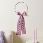 Keine Texte vorhanden. Ein rosafarbener Stoff mit Blütenstickerei hängt an einem Ring an der Wand, daneben Kerzen und ein Sofa.