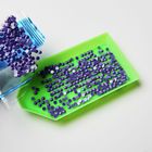 Lila Pailletten werden aus einem Beutel auf ein grünes Tablett geschüttet.