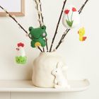 Näh-Illustration mit Filzdekorationen: Frosch, Küken, Huhn, Tulpen-Ei, und ein weißer Hase an Zweigen in einer Vase.