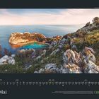 Mai. Kalenderübersicht darunter. Links felsige Küste und blaues Meer, bewachsen mit Büschen, im Abendlicht.