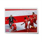 Die Zahl 05, Spieler in roten Trikots laufen jubelnd auf einen älteren Mann im Anzug zu. Unten ein kleiner Kalender.