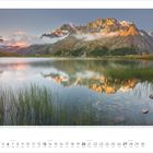 Text: "Hautes-Alpes, Frankreich". Eine ruhige Bergszene mit See, Bergen, Gras und einer Spiegelung im Wasser darunter.