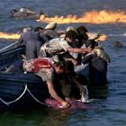 Menschen kämpfen ums Überleben in einem Boot auf stürmischer See, umgeben von Wasser und Flammen.