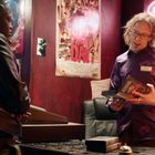 "Open" in Neonlicht. Plakat mit "TAMALE'S DAY". Zwei Personen in einem Raum mit Filmpostern. Eine steht hinter der Theke.