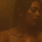 Kein Text vorhanden. Eine Frau lehnt sich gegen eine feuchte, verschwommene Wand, entspannt mit geschlossenen Augen.