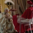 Eine Szene mit einem Priester, der einem Kardinal die Füße wäscht. Weitere Kardinäle sitzen in roten Gewändern.