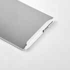 Ein weißer Stift liegt auf einem grauen Notizblock auf einer hellen Fläche.